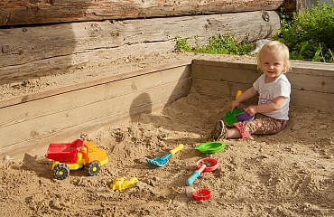 Kind sitzt im Sandkasten und spielt
