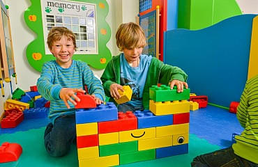 Fröhliche Kinder spielen mit großen Legobausteinen